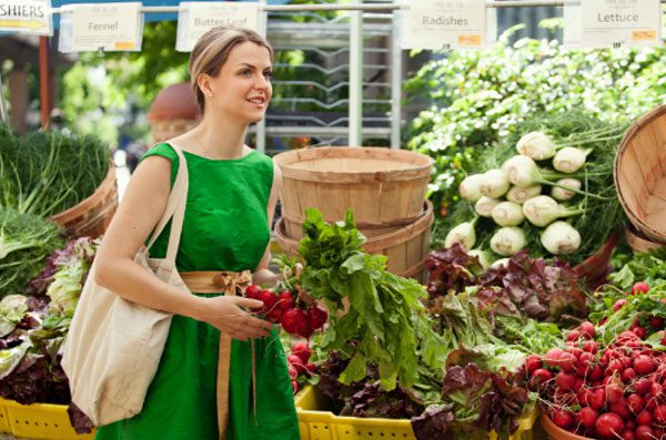Woman at the farmer's market holding a bunch of beets